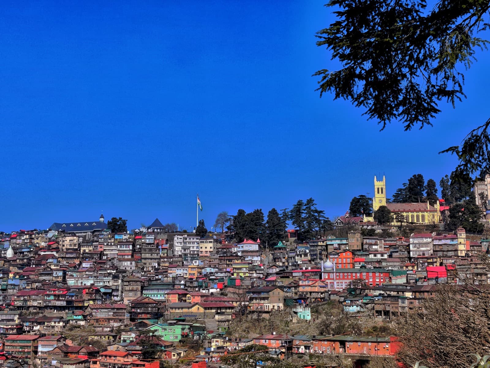 View of Shimla hillside buildings and Christ Church under a blue sky